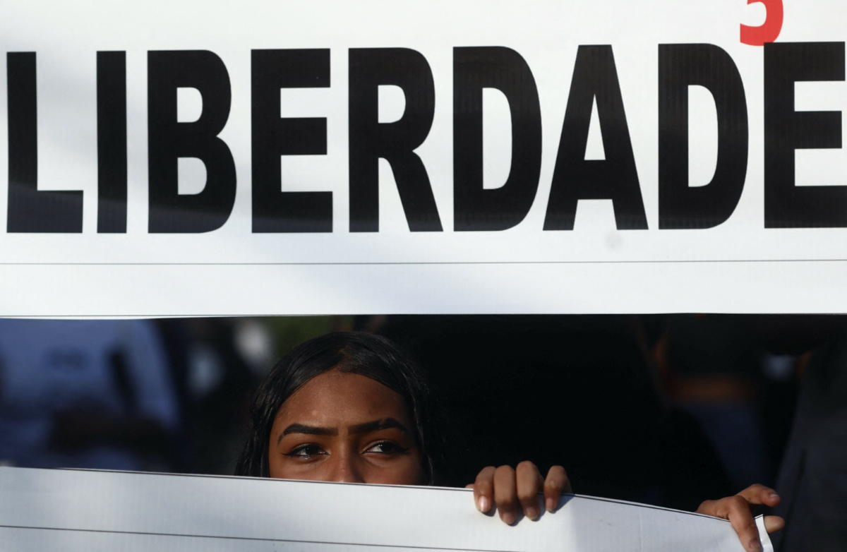 A woman looks on next to a banner which reads "Freedom" as she takes part in a demonstration against police violence during an operation at the city's slums, after a police officer was killed in Guaruja, Sao Paulo state, Brazil, on 2nd August, 2023. 