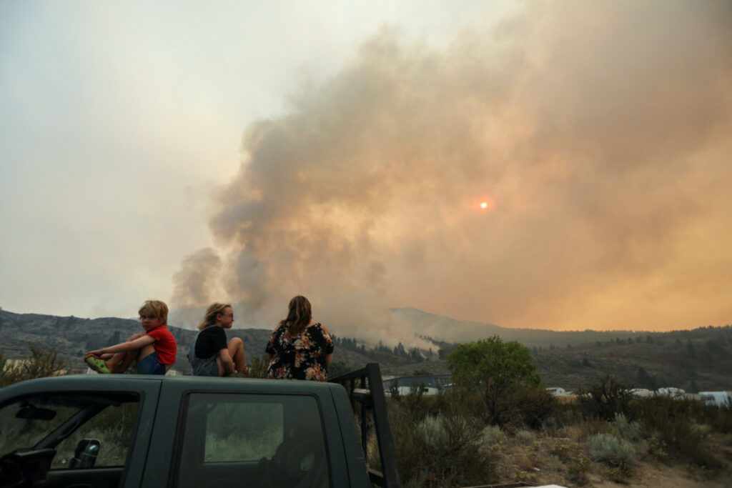 Locals gather to watch firefighting efforts amid heavy smoke from the Eagle Bluff wildfire, after it crossed the Canada-US border from the state of Washington and prompted evacuation orders, in Osoyoos, British Columbia, Canada, on 30th July, 2023.