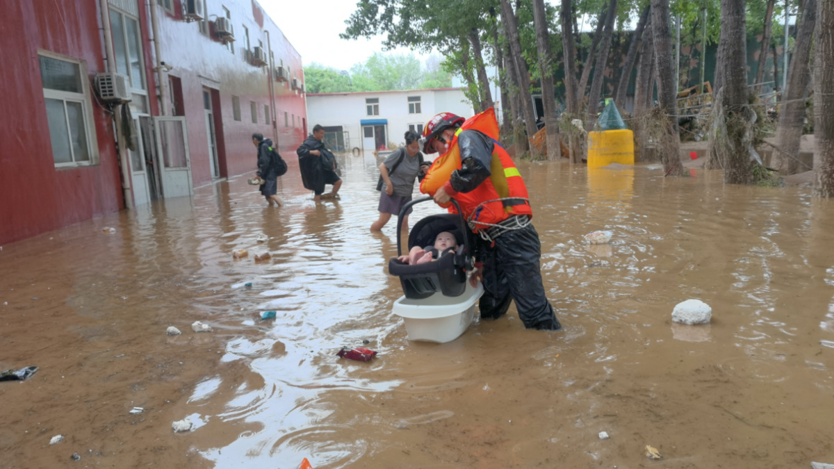 A firefighter evacuates a baby stranded by floodwaters following heavy rainfall in Fangshan district of Beijing, China, on 31st July  2023. 