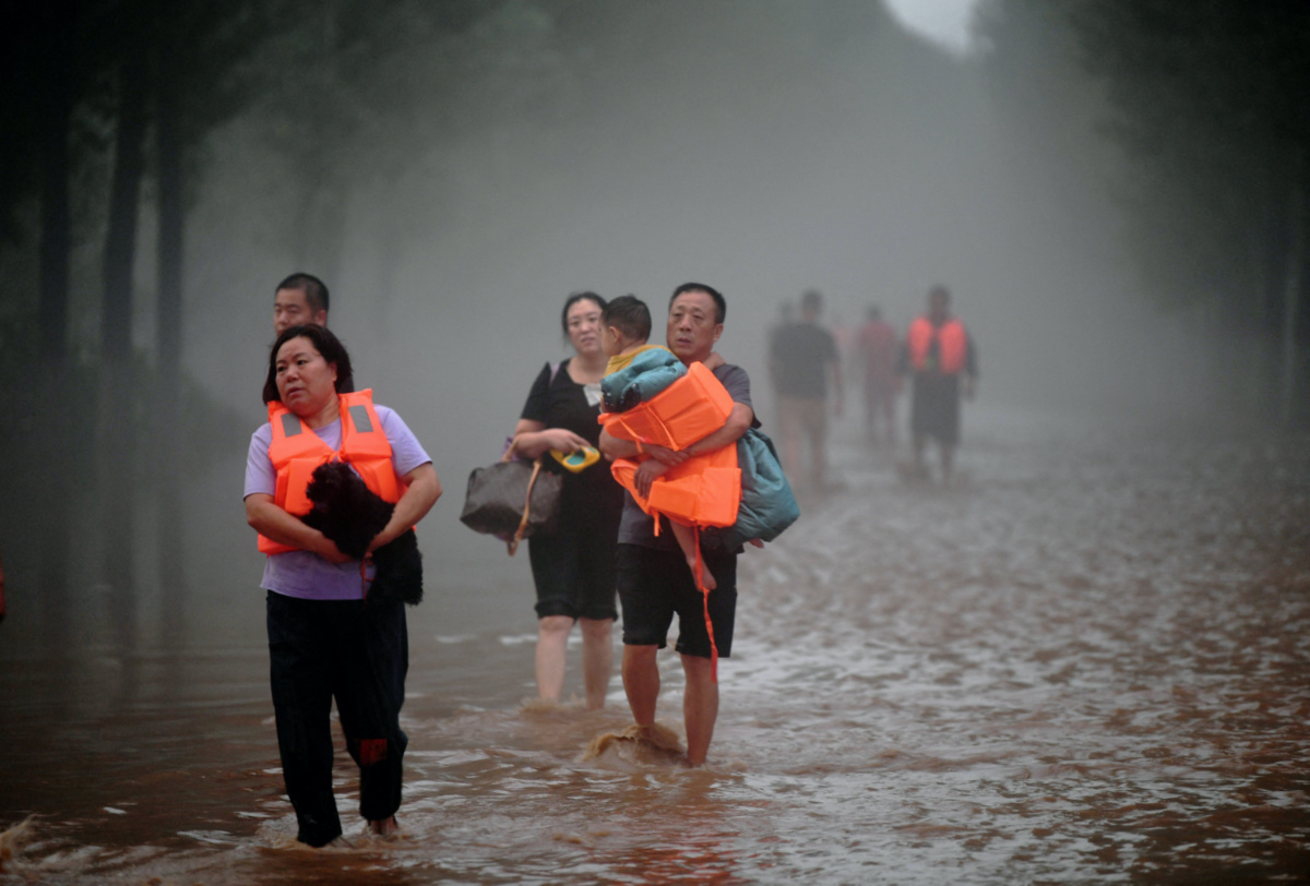Residents wade through floodwaters following heavy rainfall in Zhuozhou, Hebei province, China, on 1st August, 2023.