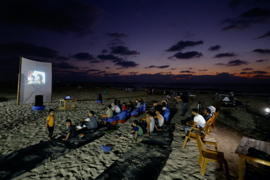 Palestinian families watch a large projector screen at a beachfront cafe during a rare cinema event, in Gaza City, on 11th August, 2023