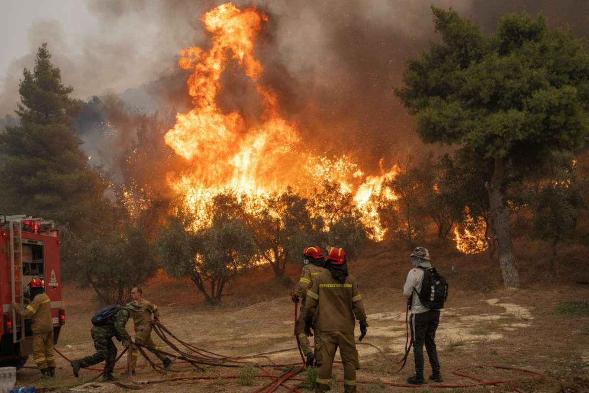 Firefighters and volunteers try to tackle a wildfire burning in the village of Hasia, near Athens, Greece, on 22nd August, 2023.