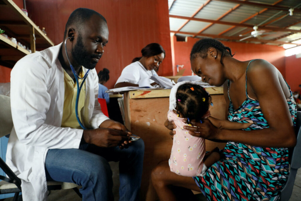 Mackenson Pierre, a doctor, treats Marie Michelle Joseph's nine-month-old baby Myleisha Moliere at the Centre Hospitalier de Fontaine, located in the impoverished neighbourhood of Cite Soleil, where the two rival gangs, G-Pep and G-9, are based, in Port-au-Prince, Haiti, on 27th July 2023.