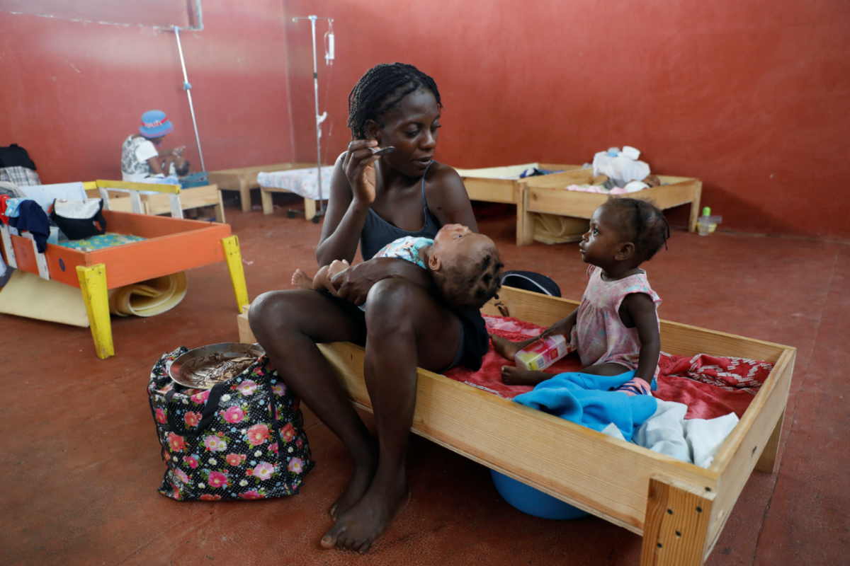 Elisha Francoirs, 25, feeds one of her friend's babies as the child receives treatment for being malnourished at the Centre Hospitalier de Fontaine, located in the impoverished neighbourhood of Cite Soleil, where the two rival gangs, G-Pep and G-9, are based, in Port-au-Prince, Haiti, on 27th July, 2023. 