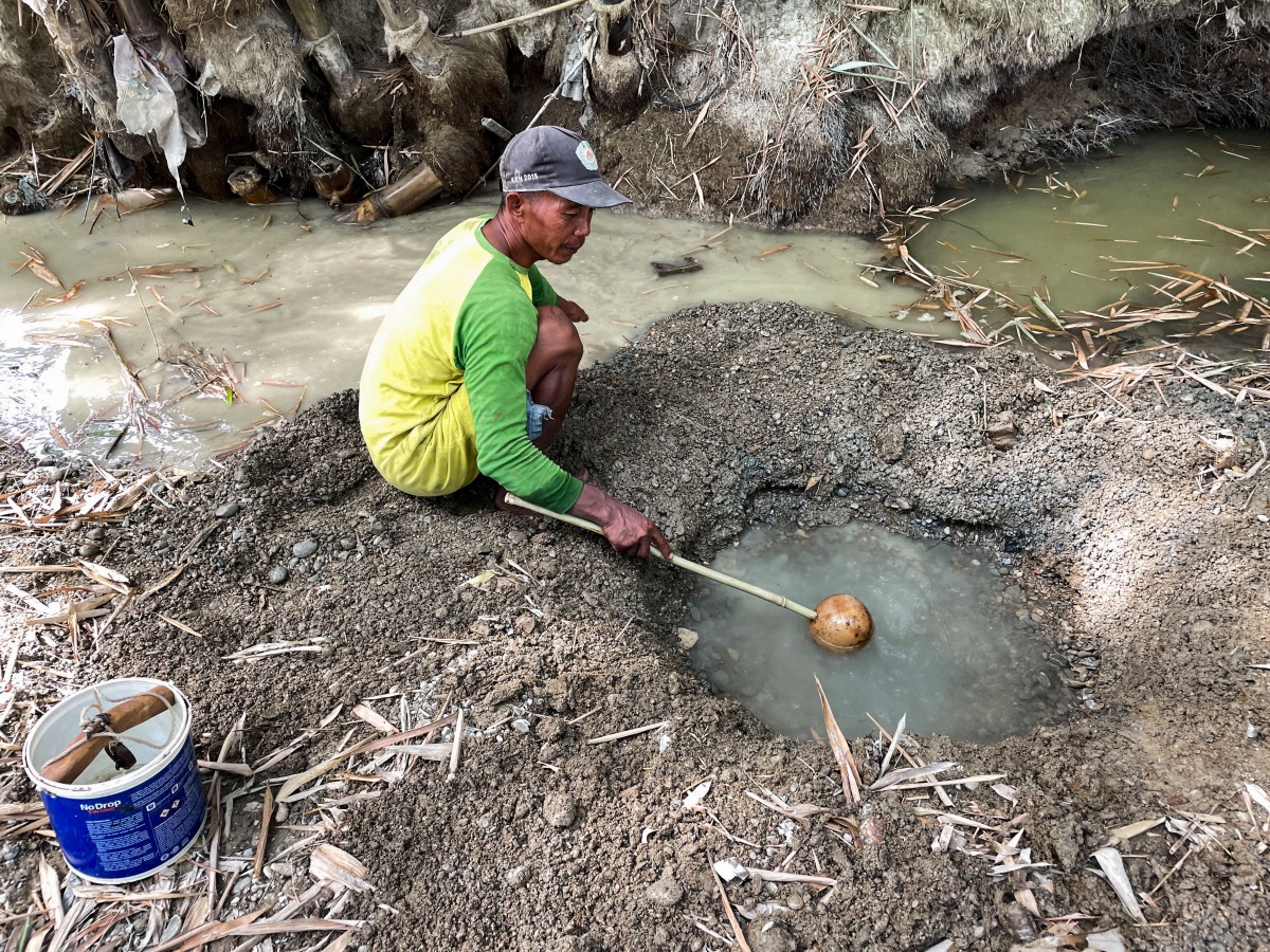 Sunardi, a 52-year-old tobacco farmer, collects murky water for daily needs from a hand-dug well on a dry riverbed, the only remainder of what was once a flowing river as drought strikes in Grobogan regency, Central Java province, Indonesia, on 27th July