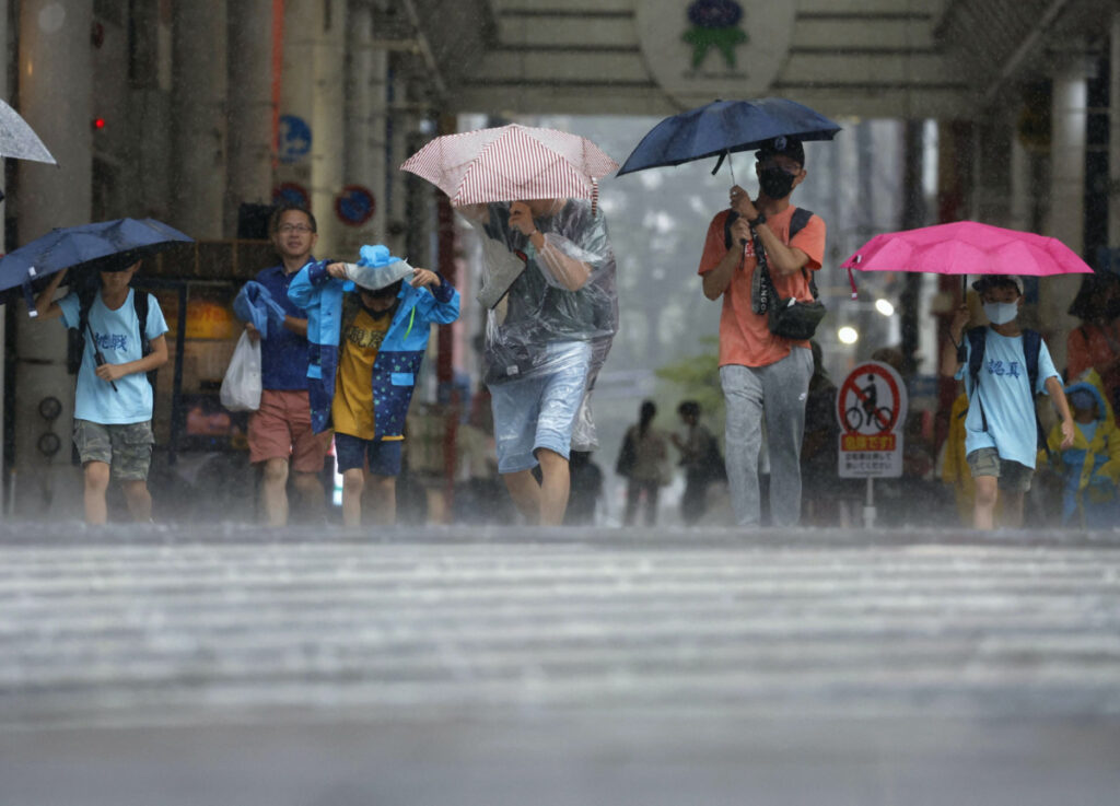 Passersby walk in a heavy rain and wind caused by Typhoon Khanun in Kagoshima on Japan's third-largest island Kyushu, on 8th August, 2023, in this photo taken by Kyodo.
