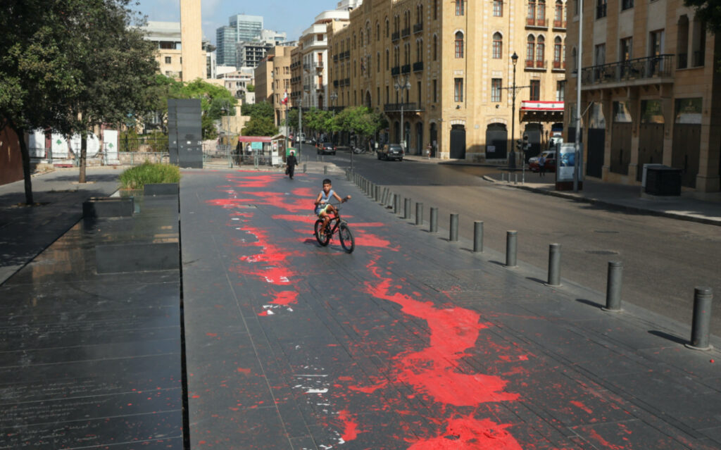 A boy rides his bicycle along a curb stained in red paint, mimicking blood, as Lebanon marks a national day of mourning for the third anniversary of the August 2020 Beirut port blast, in Beirut, Lebanon, on 4th August, 2023.