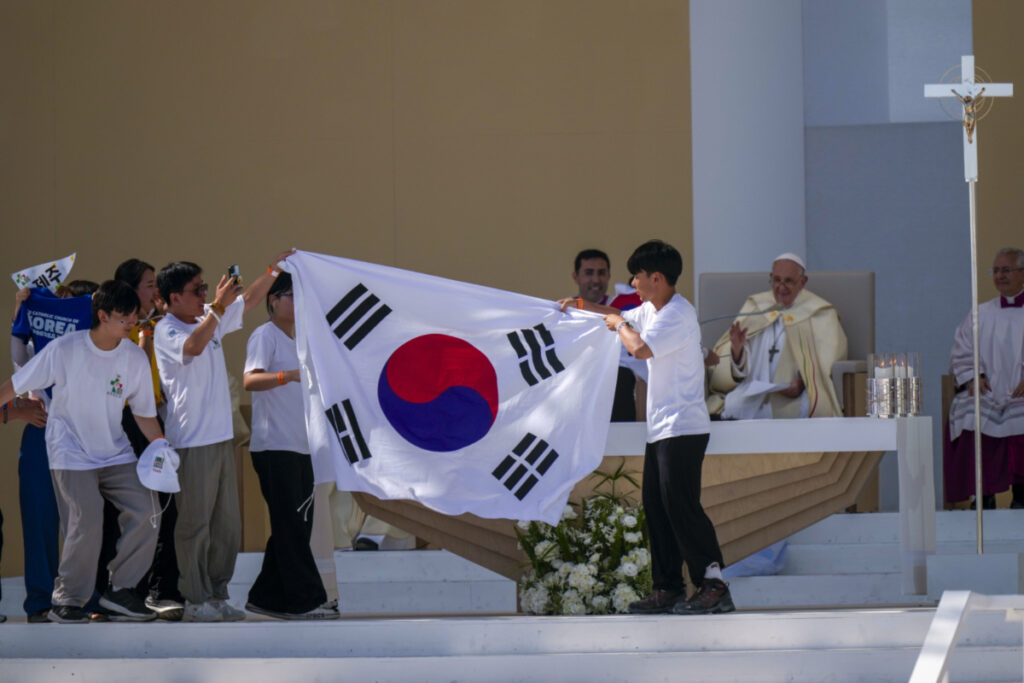 Young pilgrims from South Korea celebrate with their national flag and with Pope Francis after he announced that the next World Youth Day, will be in Seoul, South Korea in 2027, at the end of a mass at Parque Tejo in Lisbon, on Sunday, 6th August, 2023.