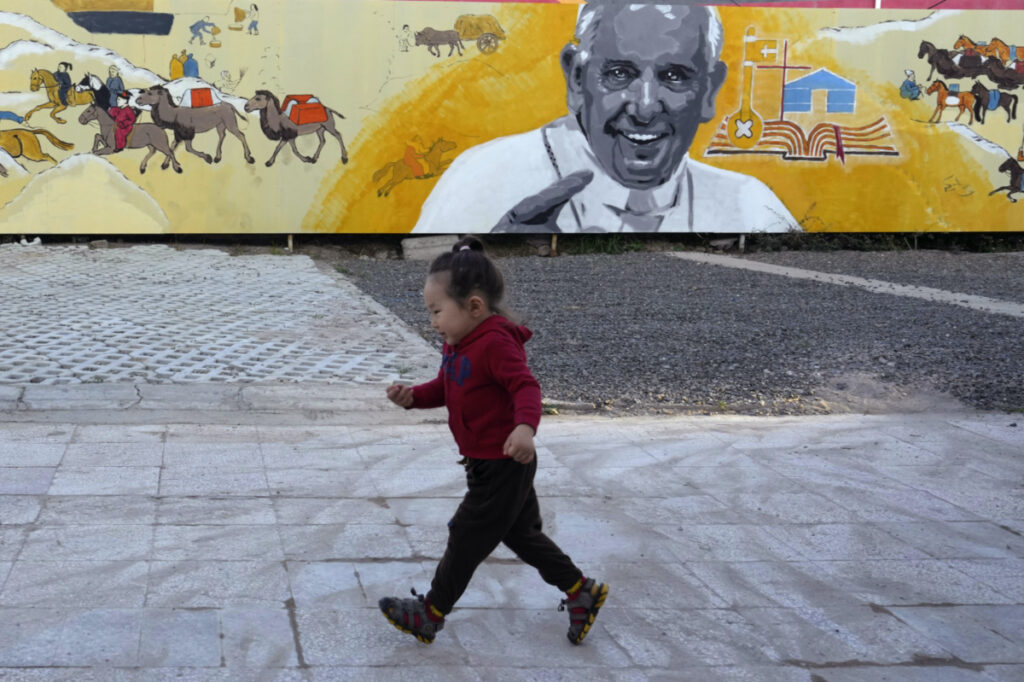 A child runs past a mural showing Pope Francis with depiction of nomadic daily life in Mongolian outside a church in Ulaanbaatar, on Monday, 28th August, 2023