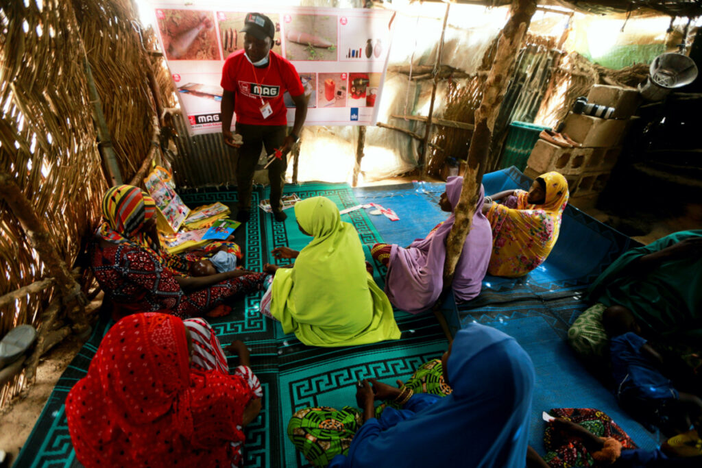 Bukar Isa, from the Mines Advisory Group, shows displaced victims of the Boko Haram insurgence how to identify marked objects of danger on the street, during a safety training at the Gubio camp in Maiduguri, Nigeria on 6th May, 2022