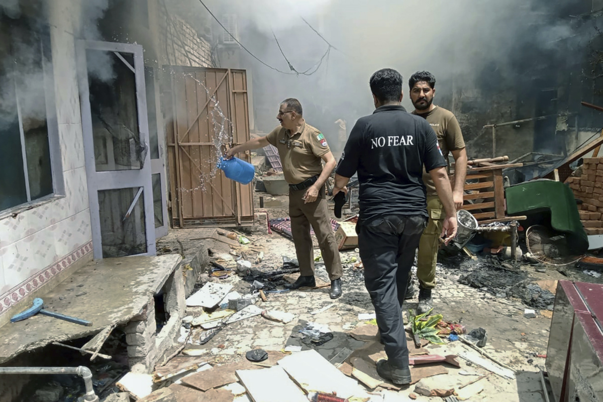In this photo provided by the district police office, a police officer pours water into a burning house in a Christian neighbourhood following an angry mob attack in Jaranwala near Faisalabad, Pakistan, on Wednesday, 16th August, 2023