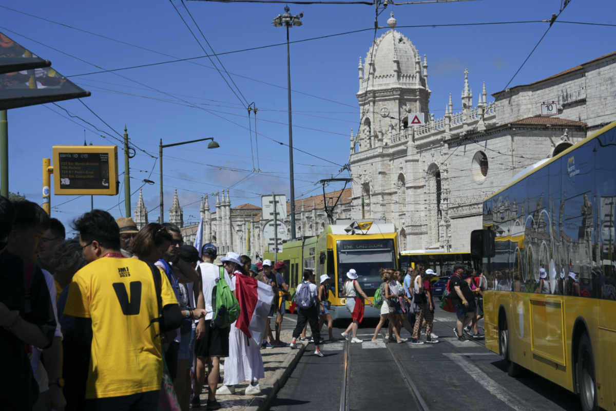World Youth Day pilgrims queue to catch public transport outside the 16th century Jeronimos monastery, in the background, in Lisbon, on Tuesday, 1st August, 2023.