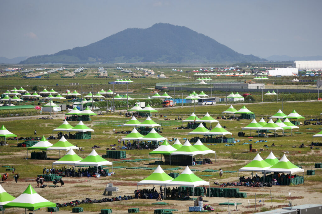 Participants gather under the shade as they prepare to leave the camping site of the 25th World Scout Jamboree in Buan, South Korea, on 8th August, 2023