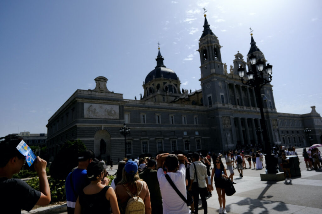 People queue in the sun outside Almudena Cathedral as they wait to enter the Royal Palace during the third heatwave of the summer in Madrid, Spain, on 8th August, 2023