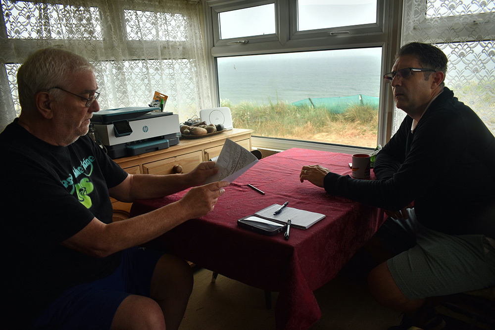 Kevin Jordan, left, and his neighbour Simon Measures discuss an old land registry diagram and the coastal erosion they’ve seen in front of their homes, Hemsby, England, on 20th June, 2023.