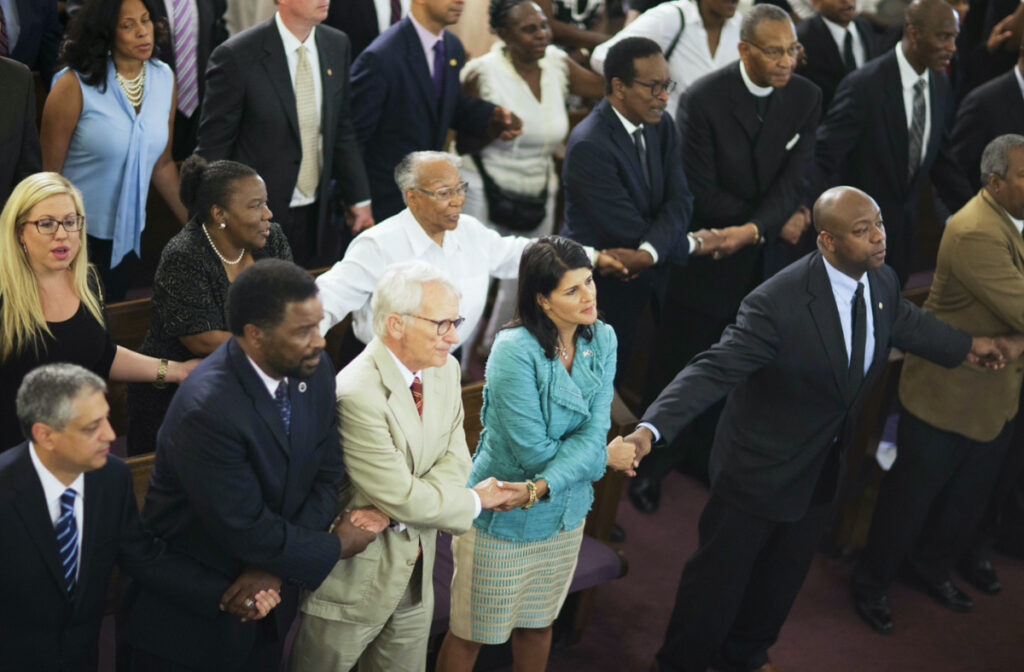 Then-South Carolina Governor Nikki Haley, centre right, joins hands with Charleston Mayor Joseph Riley, left, and Senator Tim Scott, right, at a memorial service at Morris Brown AME Church in Charleston, South Carolina, on 18th June, 2015.