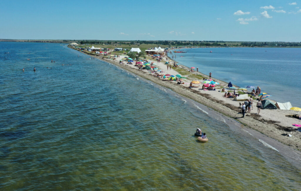 People rest on a narrow beach of the Tylihul river that widens into a broad estuary, amid Russia's attack on Ukraine, in Mykolaiv region, Ukraine, on 29th July, 2023.