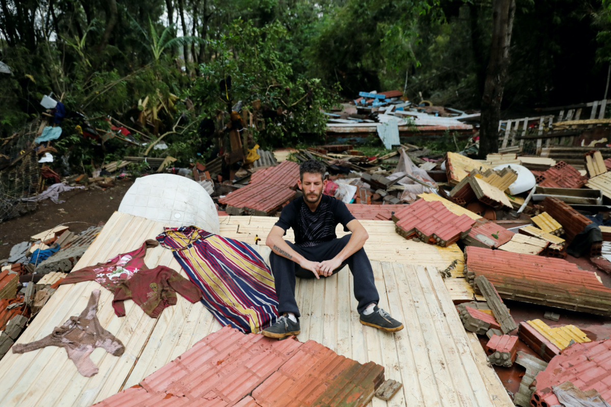 Flood survivor Miguel Rutigliano Bieleski sits on the wreckage of his house as he gets emotional after finding clothes of his wife Ariel Armani, his daughter Yasmin and his son Miguel Junior, that are still missing, after the passage of the extratropical cyclone that hit the region, Lajeado, Brazil, on 8th September, 2023