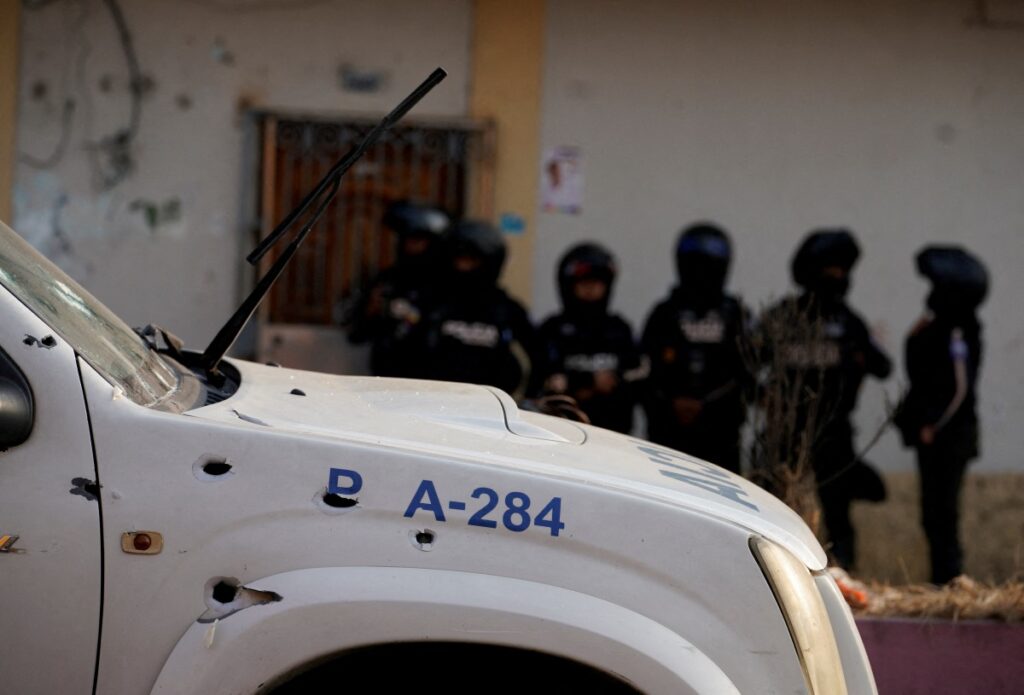 Police officers stand guard near a bullet-riddled police car at a crime scene where colleagues were killed in response to prisoner transfers from overcrowded prisons, prompting President Guillermo Lasso to declare a state of emergency in two provinces, in Guayaquil, Ecuador, on 1st November, 2022