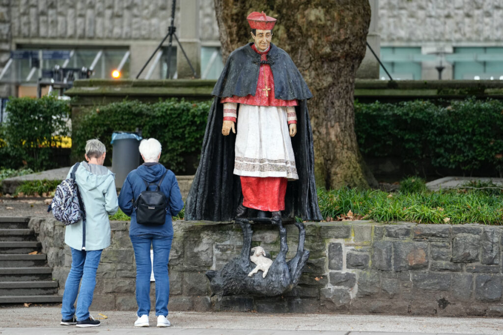 People stand at the monument of German Cardinal Franz Hengsbach beside the cathedral in the city center of Essen, western Germany, Friday, on 22nd September, 2023.