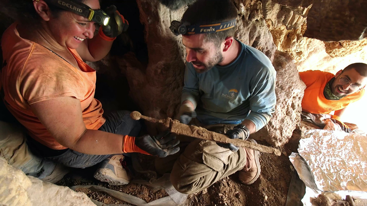 Archaeologists remove swords found within a crevice in a cave above the Dead Sea in eastern Israel in August 2023.