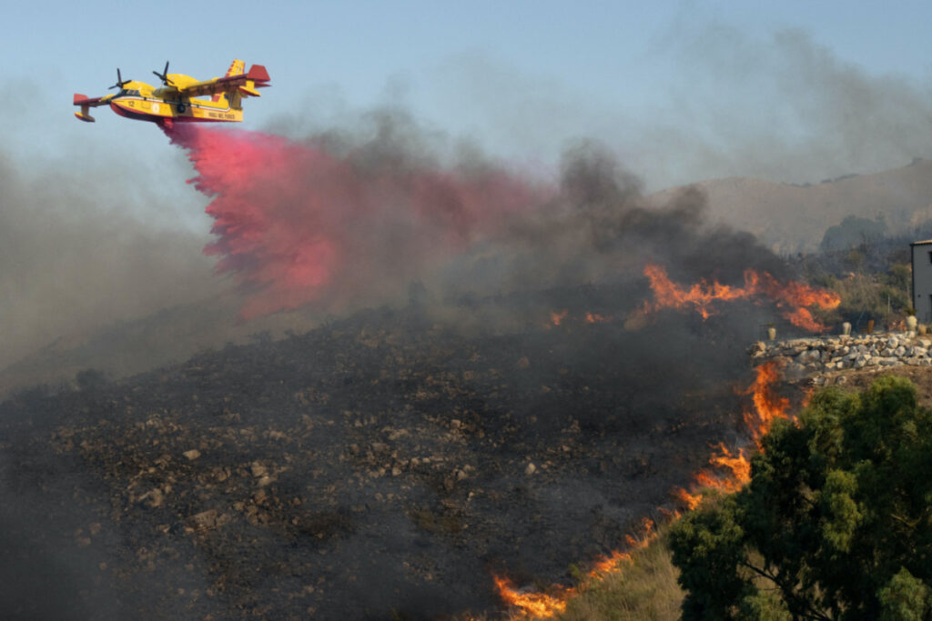A Canadair aircraft drops flame retardant on burning vegetation in Sicily's Trapani, Italy, on 27th August, 2023