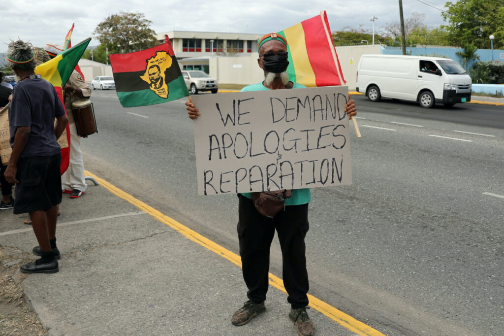 A protester holds a sign during a rally to demand that the United Kingdom make reparations for slavery, ahead of a visit to Jamaica by the Duke and Duchess of Cambridge as part of their tour of the Caribbean, outside the British High Commission, in Kingston, Jamaica on 22nd March, 2022.