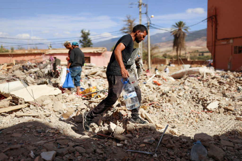 A man walks on the rubble as people look on, in the aftermath of a deadly earthquake, in Amizmiz, Morocco, on 10th September, 2023