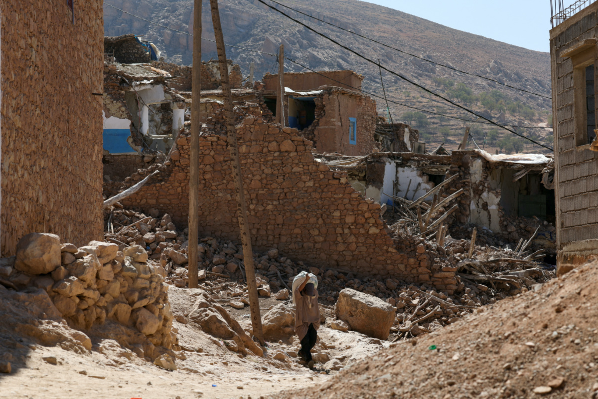 A man carries a heavy bag on his back as he is surrounded by rubble following a deadly earthquake in Douzrou village, in Morocco, on 13th September, 2023