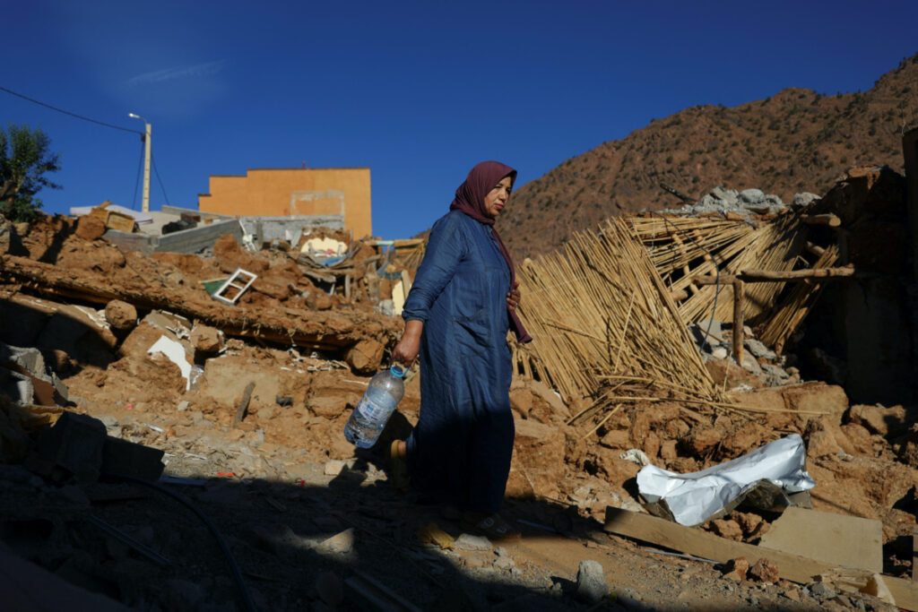 A woman carries a bottle, as she walks near rubble, in the aftermath of a deadly earthquake, in a hamlet on the outskirts of Talaat N'Yaaqoub, Morocco, on 11th September, 2023