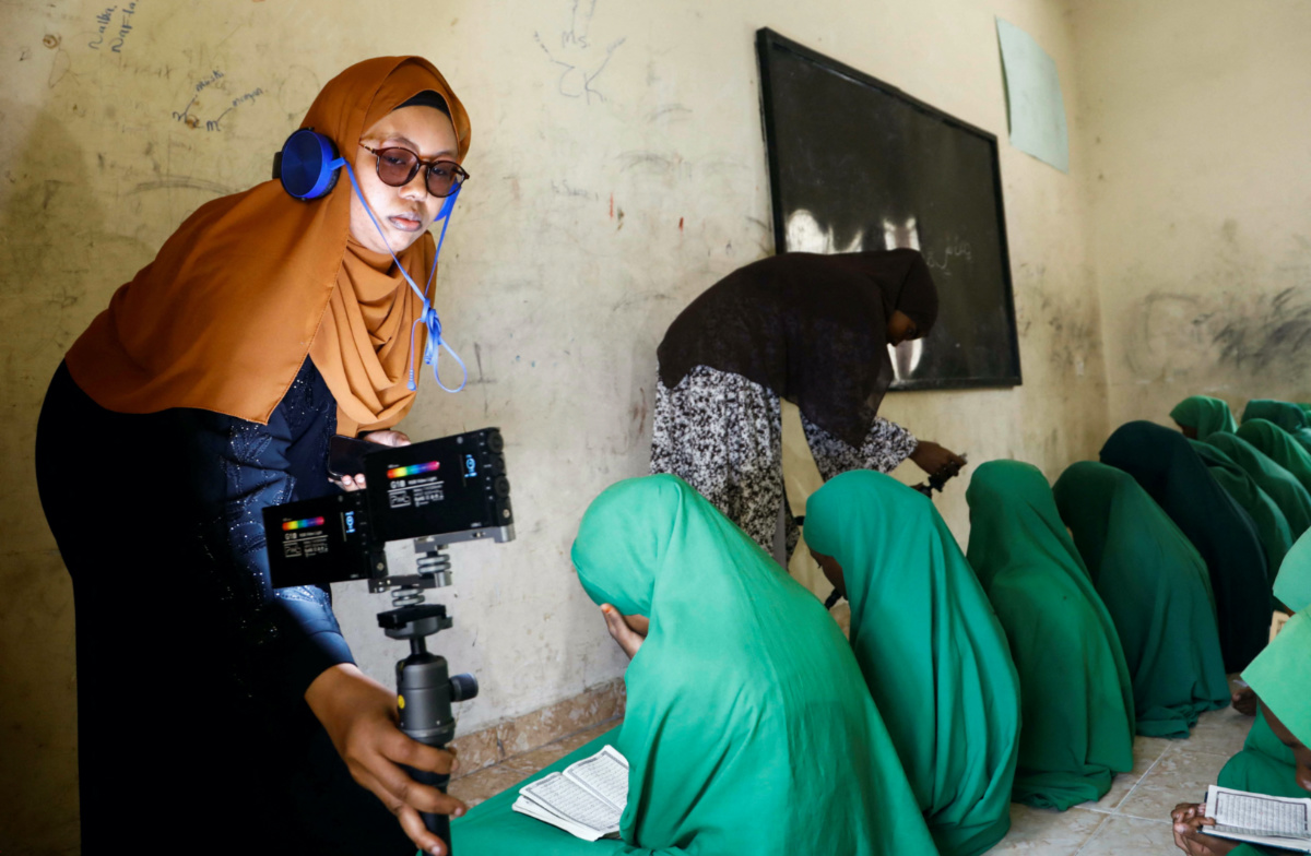 Fathi Mohamed Ahmed and Shukri Mohamed Abdi, journalists at Bilan Media, Somalia's first all-women media team, use mobiles to film girls at the Bondhere Kindergarten and Orphan Center during a news gathering assignment in Mogadishu, Somalia, on 20th August, 2023.