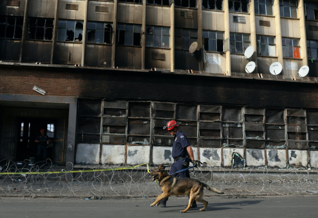 A member of the K9 unit walks with the dog at the scene of a deadly blaze in Johannesburg, South Africa, on 1st September, 2023.