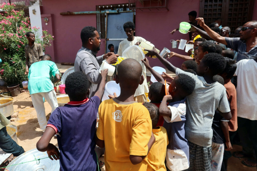 People hold pots as volunteers distribute food in Omdurman, Sudan, 3rd September, 2023