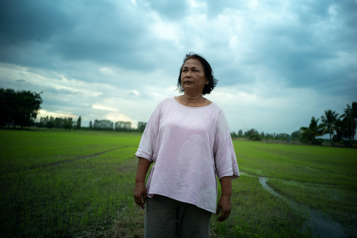 Sripai Kaeo-eam, 58, a farmer who is struggling to repaying her loans, poses in front of her rice field during an interview with Reuters in Chainat province, Thailand, on 30th August, 2023