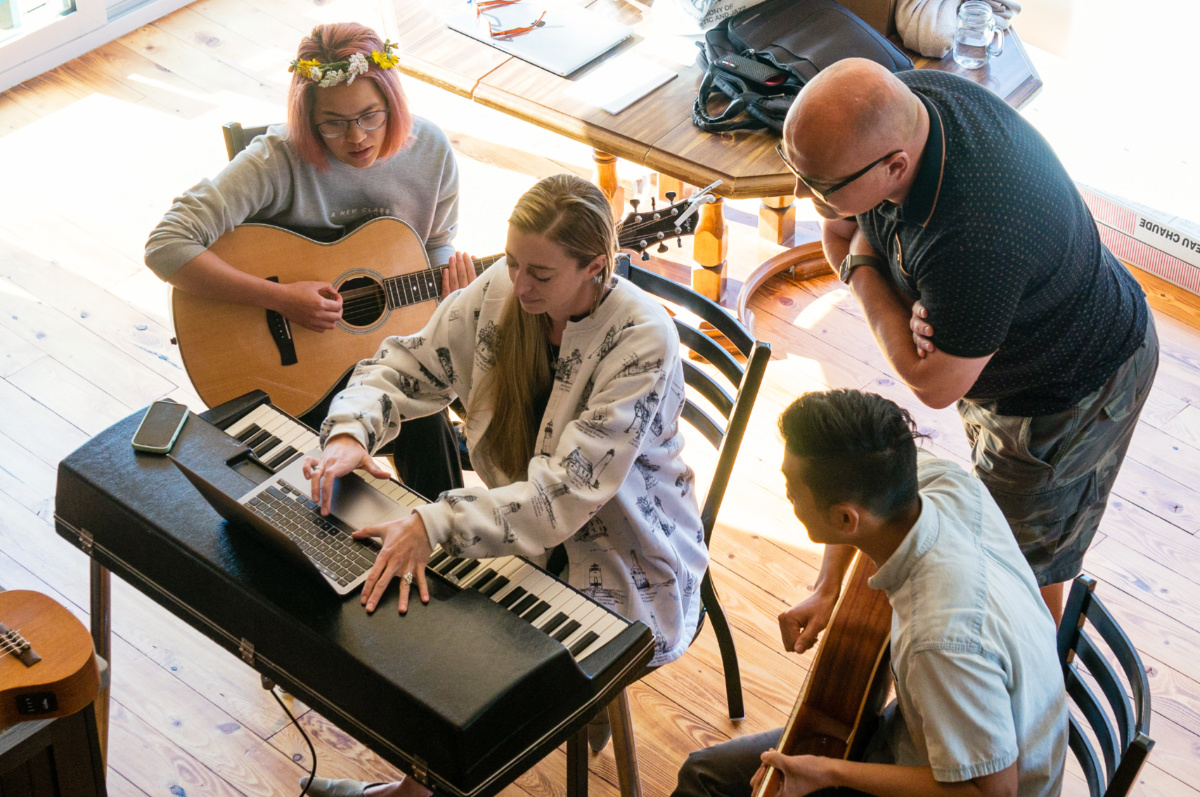 Daniel Whitehead, Valerie Guerra, Niki Jung and Paul Lee huddle together around a keyboard during a day of the retreat. 