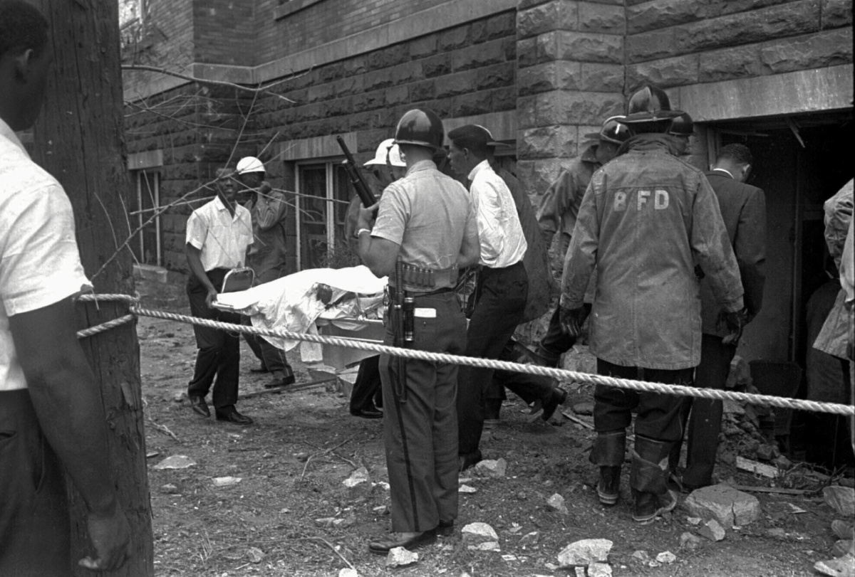 Firemen and ambulance attendants remove a covered body from Sixteenth Street Baptist Church, where an explosion ripped though the structure during services, killing four black girls, on 15th September, 1963