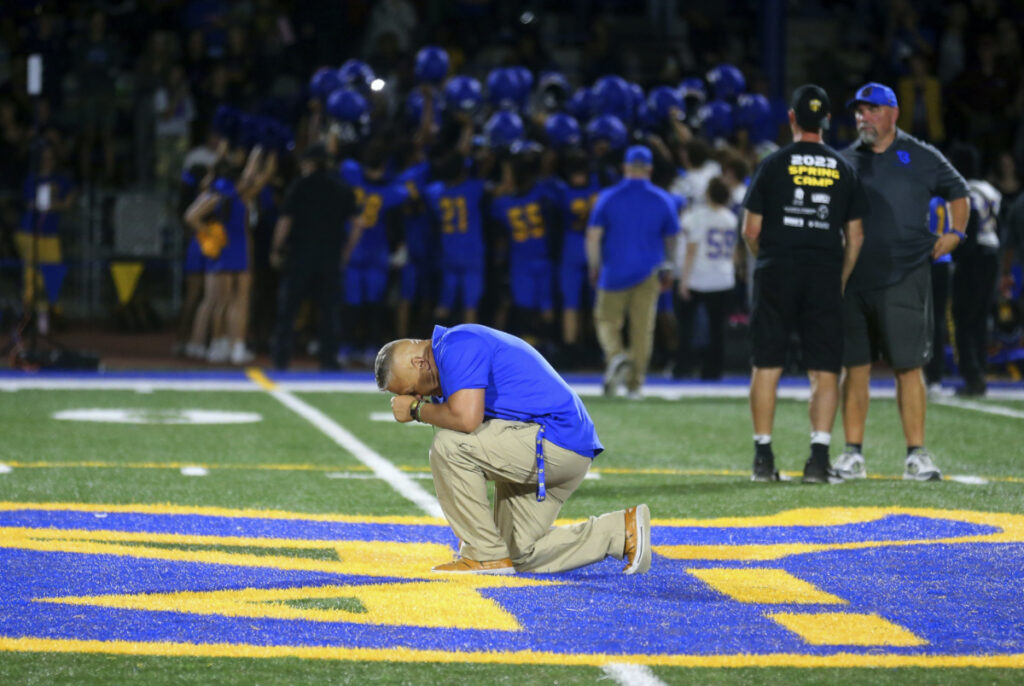 Bremerton High School assistant coach Joe Kennedy takes a knee and prays at the 50-yard line after Bremerton's win over Mount Douglas in a high school football game at Bremerton Memorial Stadium in Bremerton, Washington, on 1st September, 2023