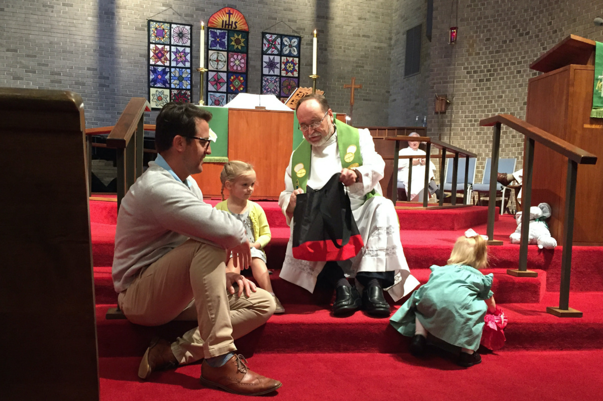 Senior Pastor Wolfgang Herz-Lane gives a Martin Luther toy to a child during a church service. 