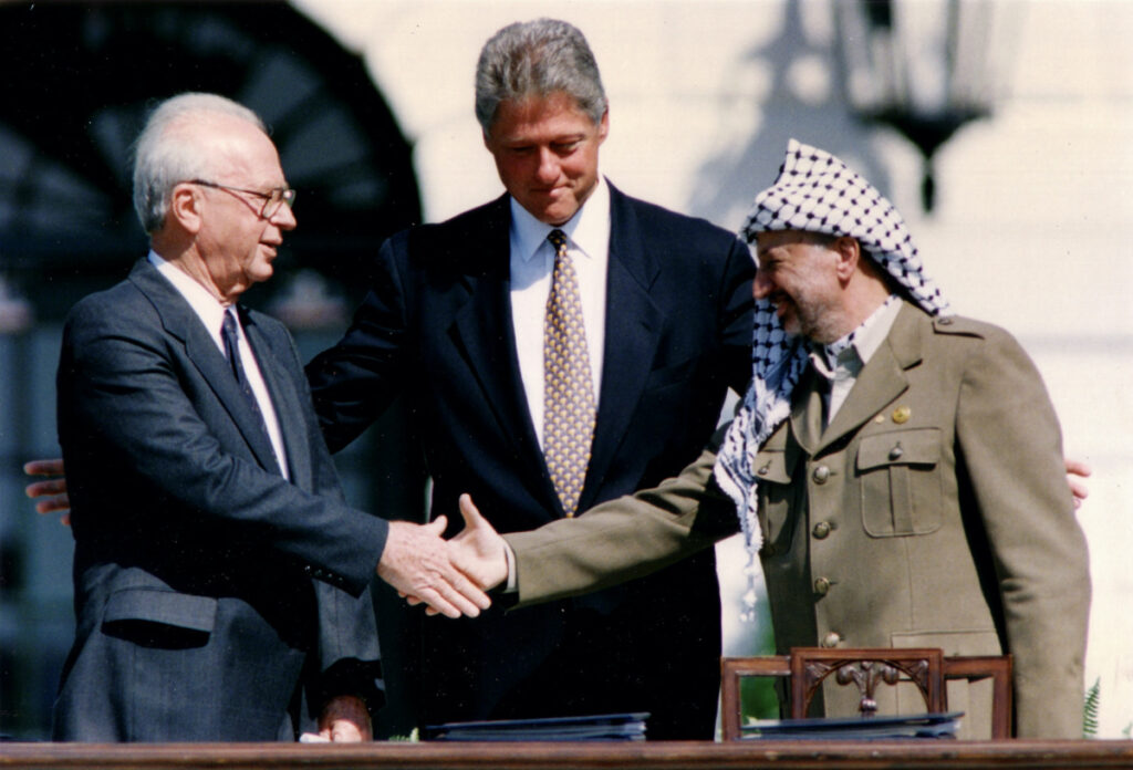 PLO Chairman Yasser Arafat shakes hands with Israeli Prime Minister Yitzhak Rabin as US President Bill Clinton stands between them, after the signing of the Israeli-PLO peace accord, at the White House in Washington on 13th September, 1993.