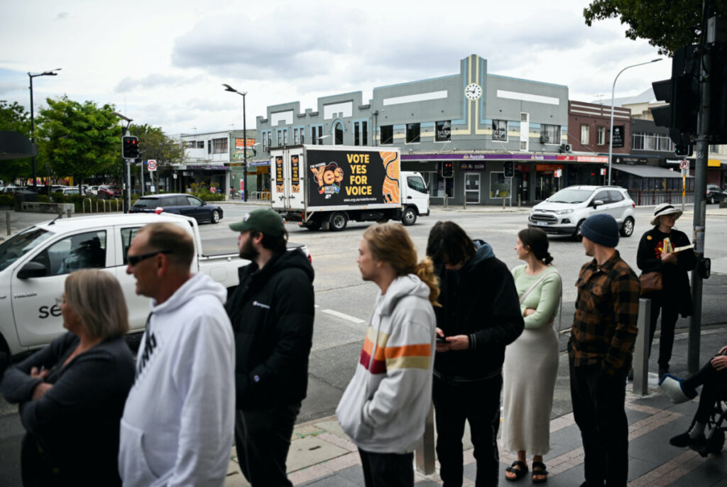 'Yes' campaigners drive past voters lining up at a polling booth during The Voice referendum in Queanbeyan, Australia, on 14th October, 2023