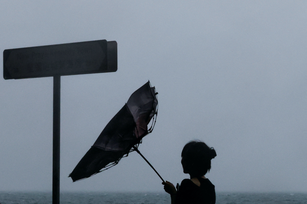 A woman struggles with an umbrella while walking against strong wind, as Typhoon Koinu approaches, in Hong Kong, China, on 8th October, 2023