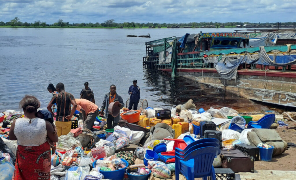 People stand among the belongings of the passengers of the boat capsized on the Congo river late on Friday in Mbandaka, Democratic Republic of Congo, on 16th October, 2023