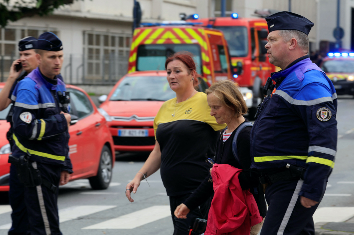 French police escort women near the Lycee Gambetta-Carnot high school after a teacher was killed and several people injured in a knife attack in Arras, northern France, on 13th October, 2023