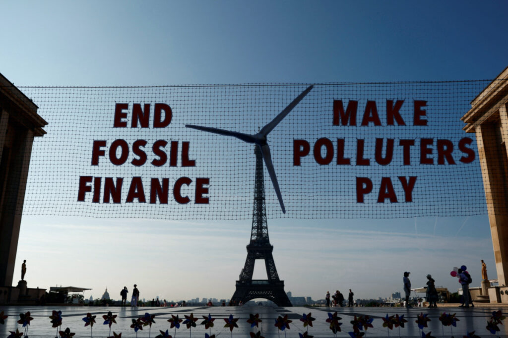 Activists with Glasgow Actions Team and 350.org hold a floating "invisible banner" that will appear to transform the Eiffel Tower into a wind turbine to welcome world leaders on the eve of the Summit for a New Global Financial Pact, at the Trocadero Square in Paris, France, on 21st June 2023.