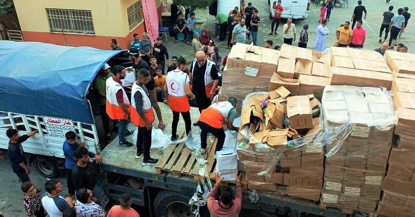 Members of the Palestine Red Crescent Society distribute aid to people in Deir al-Balah, in the central Gaza Strip, in this handout picture released on 25th October, 2023