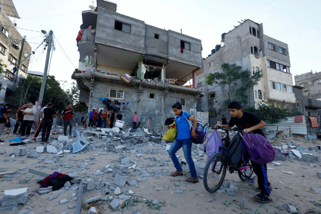 Young Palestinians walk in front of a damaged house in the aftermath of Israeli strikes in Khan Younis in the southern Gaza Strip, on 30th October, 2023