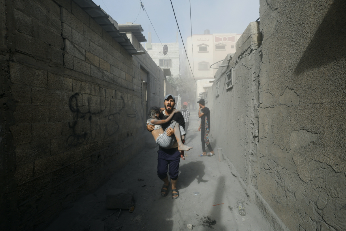 A Palestinian man carries a child casualty at the site of Israeli strikes on houses, as the conflict between Israel and Palestinian Islamist group Hamas continues, in Khan Younis in the southern Gaza Strip, on 26th October, 2023