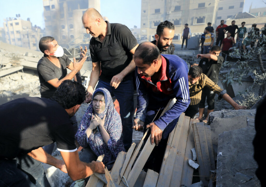 A Palestinian woman is assisted, as people search for casualties at the site of an Israeli strike on a residential building in Gaza City, on 25th October, 2023