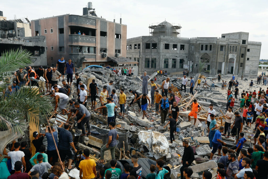 Palestinians walk among the rubble of a building destroyed in Israeli strikes, in the southern Gaza Strip, on 9th October, 2023.