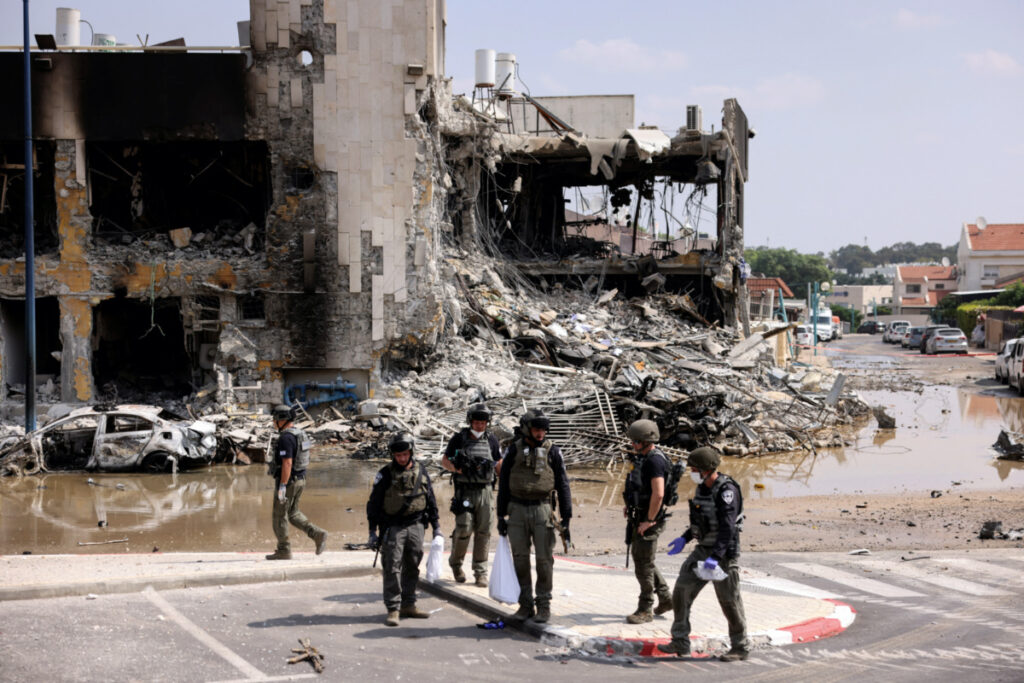 Israeli security gather near a rifle at the site of a battle following a mass infiltration by Hamas gunmen from the Gaza Strip, in Sderot, southern Israel, on 8th October, 2023